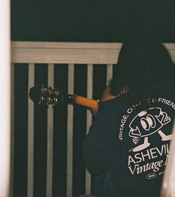 Student playing guitar on a porch at night