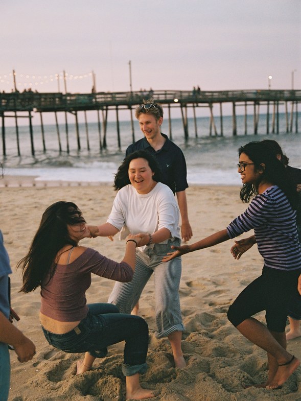 Friends playing on the beach near a pier