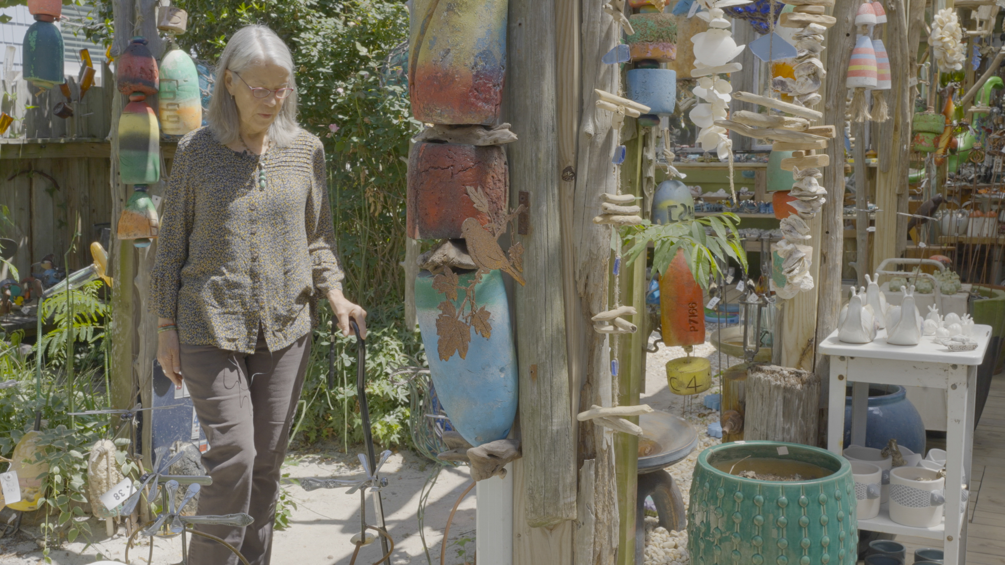 Susan Evans walks through rows of old fishing buoys, repainted and hung as decor for the outside of her art gallery.