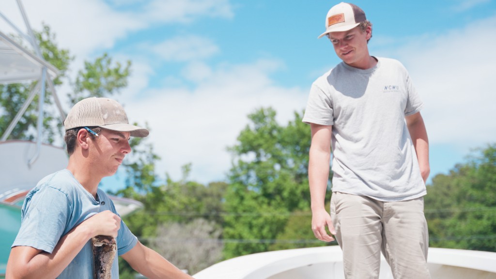 Burcham Harrison and Campbell Crisler share notes while inspecting a damaged boat during working hours at Harrison Boatworks.