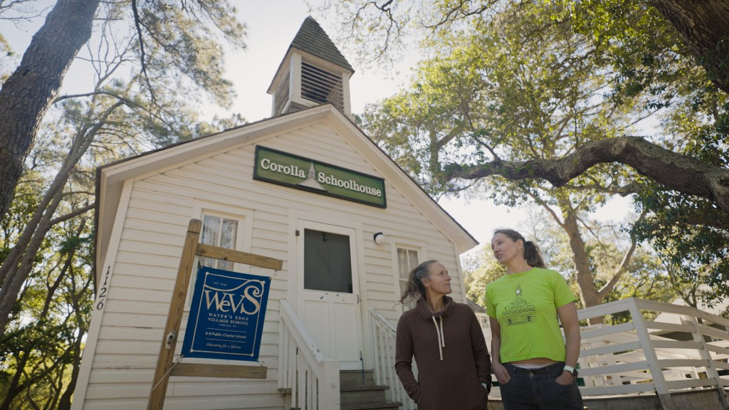 Meghan Agresto and Sylvia Wolff stand in front of the original schoolhouse that now houses Waters Edge Village School (WEVS) students.